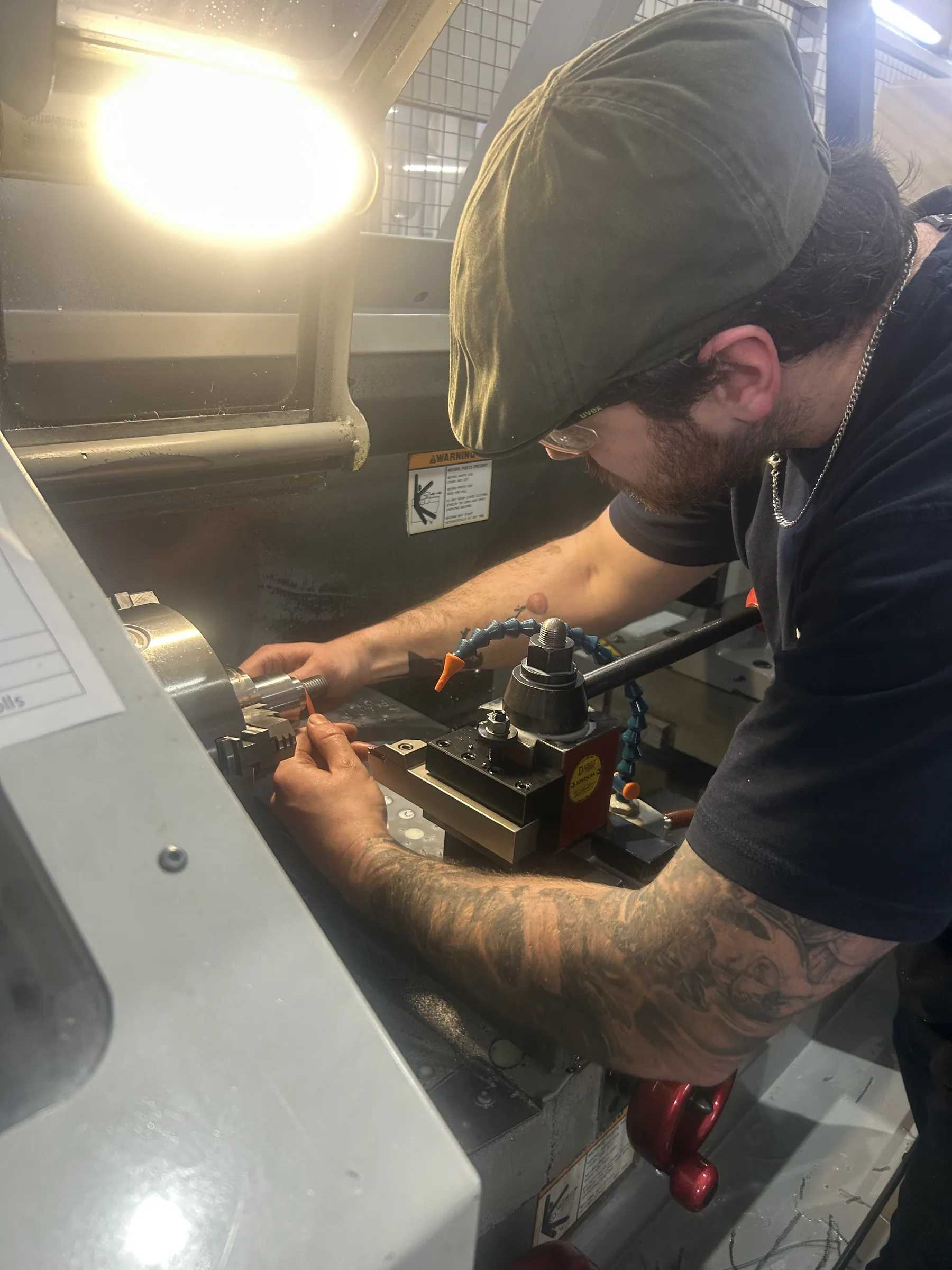 Machinist working at a Haas CNC lathe in the Gemini tool room