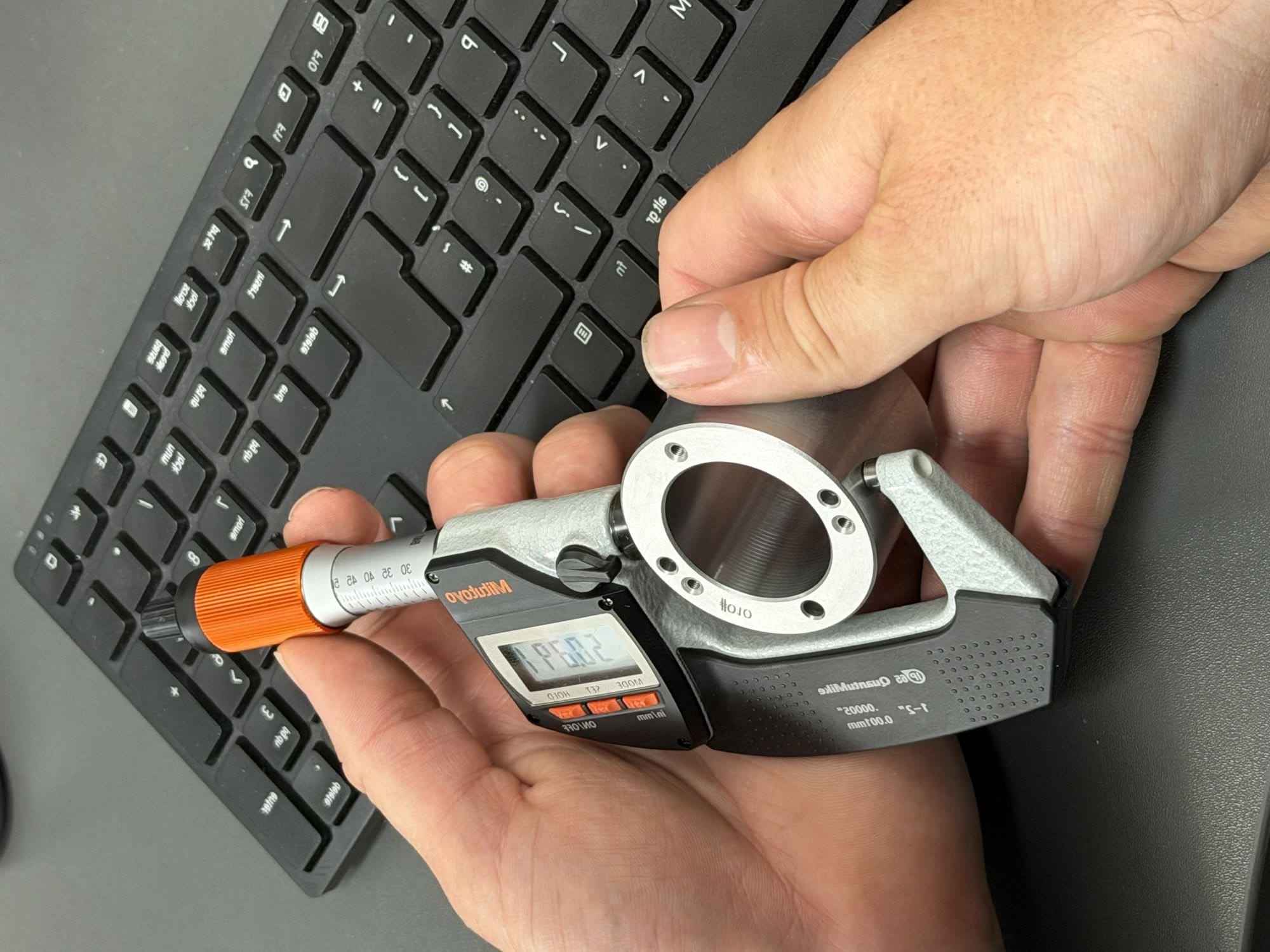 Measuring a machined plastic part with a micrometer at Gemini